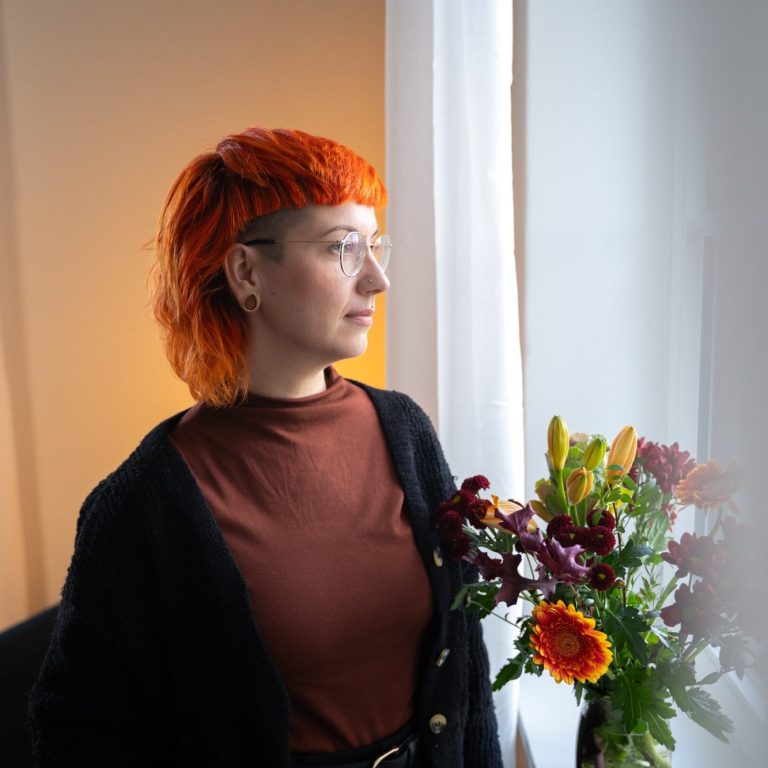 Jule am Fenster Jule steht am Fenster der Praxis und schaut nach draußen. Auf dem Fensterbrett steht ein bunter Blumenstrauß.